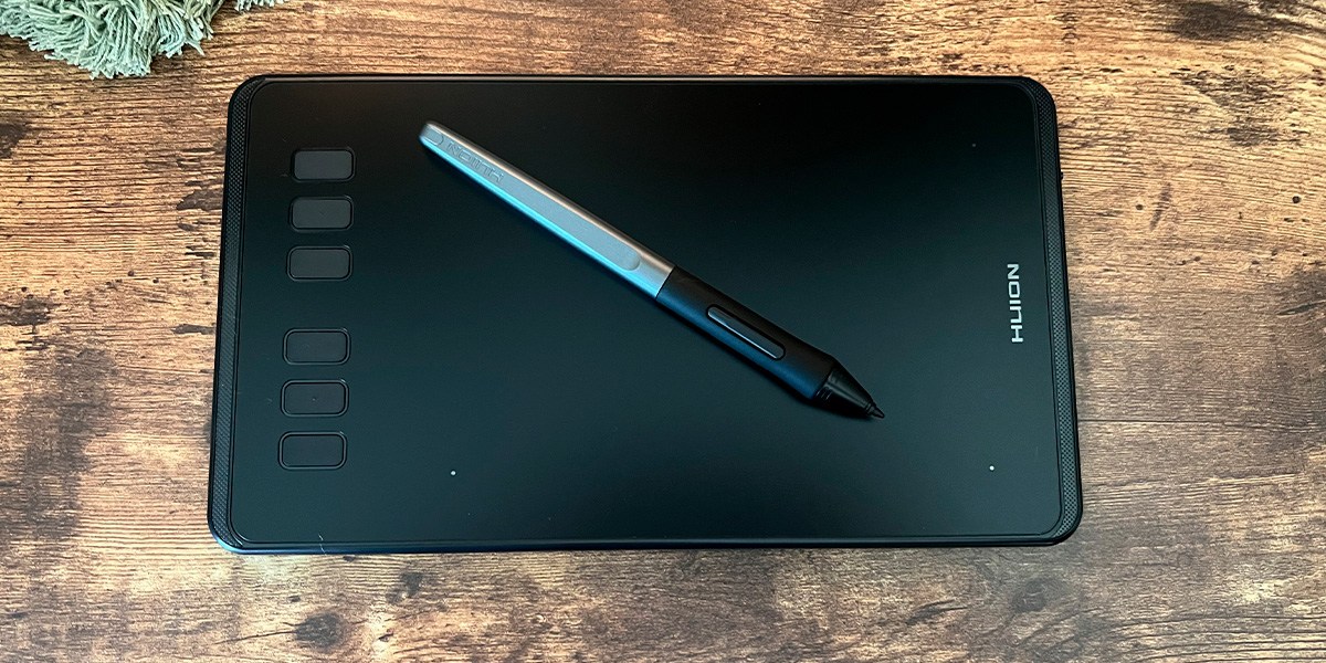 The Huion Inspiroy H640P with pen on wooden background
