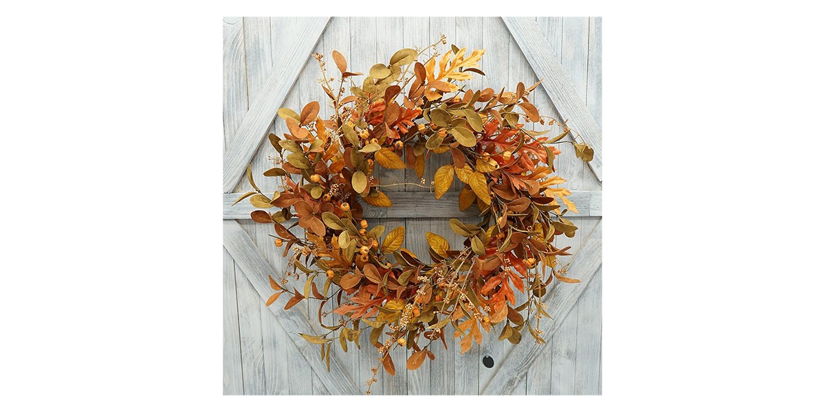 An artificial wreath with pumpkins Berries and leaves on it