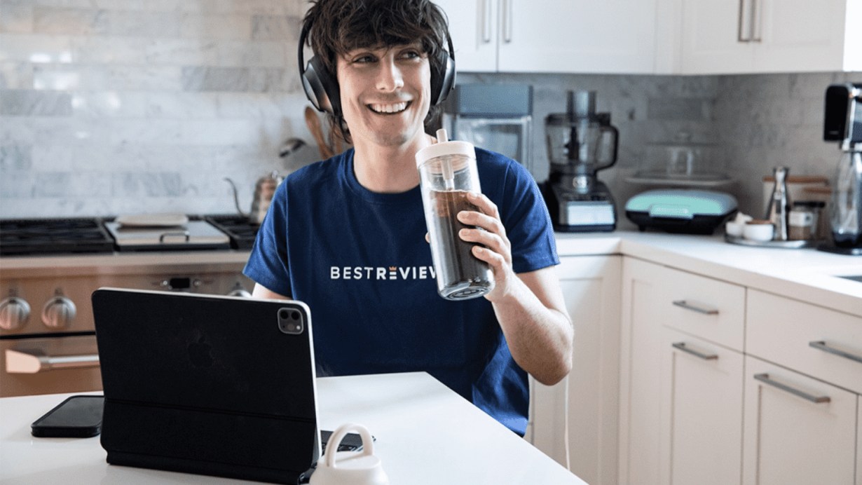 A young person using Apple Smart Keyboard Folio and drinking coffee A young person using Apple Smart Keyboard Folio and drinking coffee