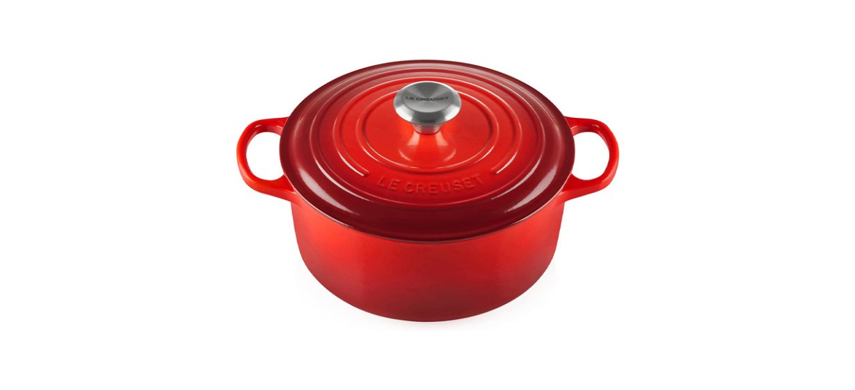 a round, red enameled cast iron dutch oven with a lid that has a knob on top of it